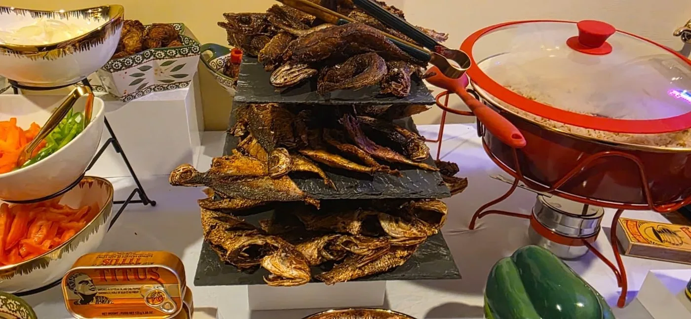 Tiers of fried fish stacked on the buffet beside a chafing dish of rice